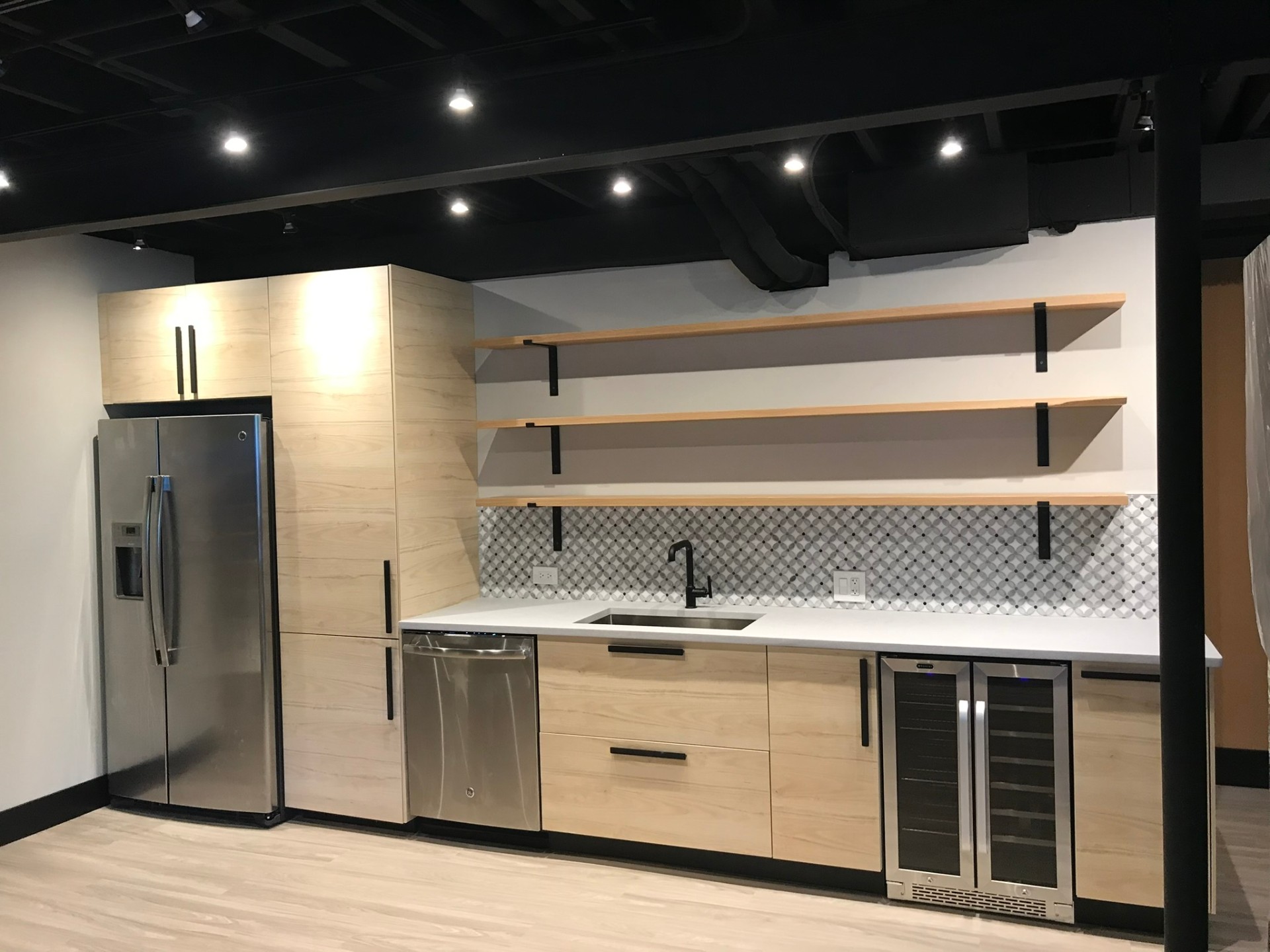 Finished basement remodel with custom wet bar, built-in shelving, and warm accent lighting