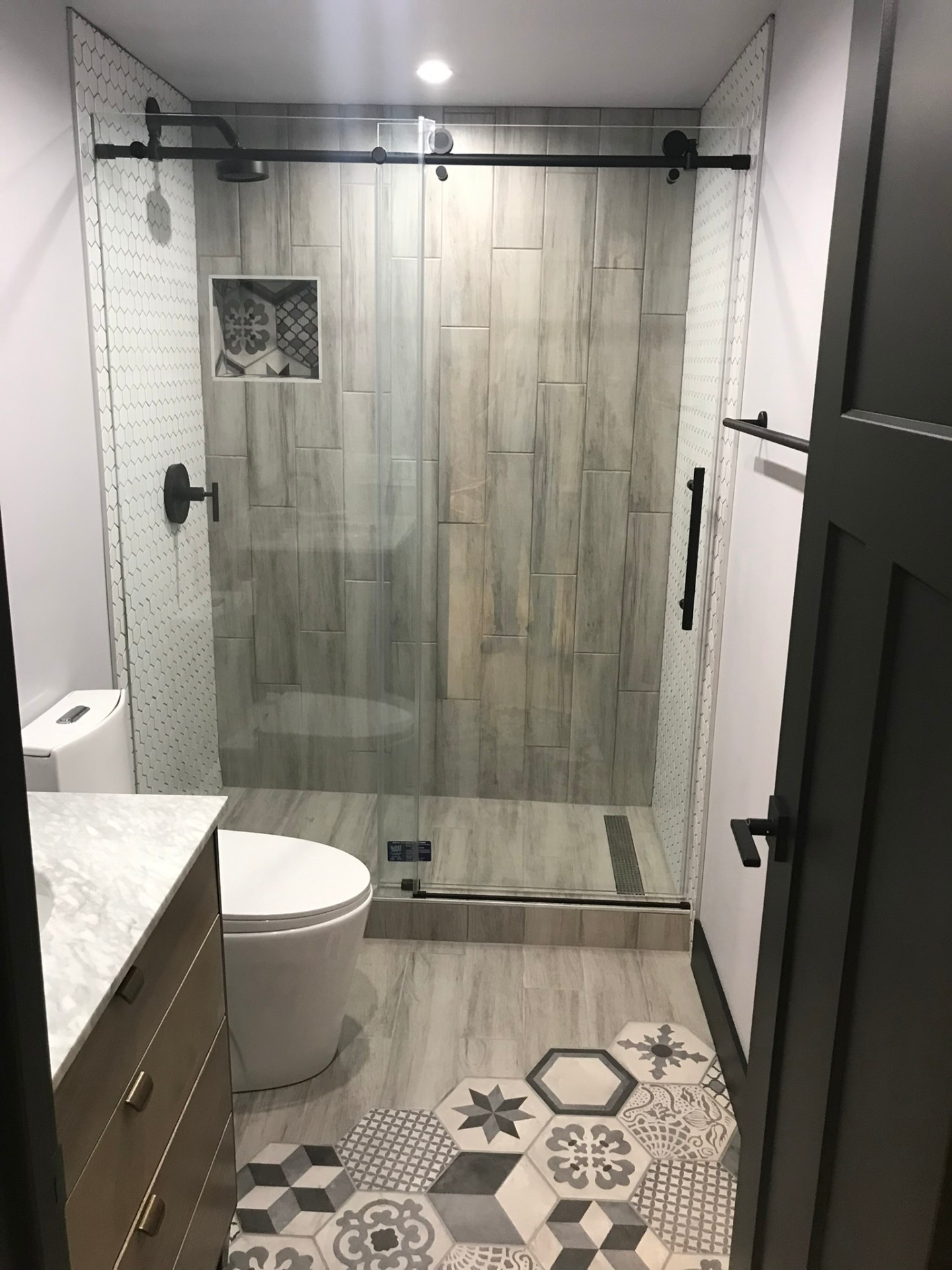 Modern bathroom remodel featuring a curbless walk-in tile shower with glass enclosure and custom vanity
